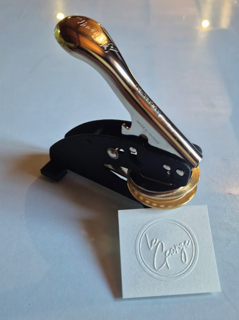 Curved-handle embosser — embossing test validated before shipping.