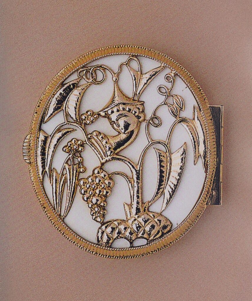 Round silver-and-enamel bonbonnière with chased and gilded floral and grape motifs against an ivory ground.