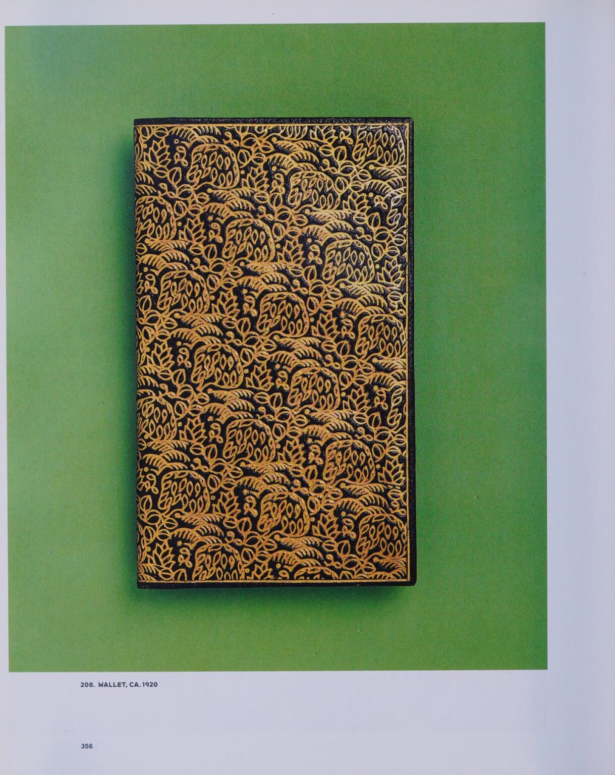 Rectangular black leather wallet richly tooled and gilt with a dense all-over rococo foliate pattern, on an emerald-green ground.