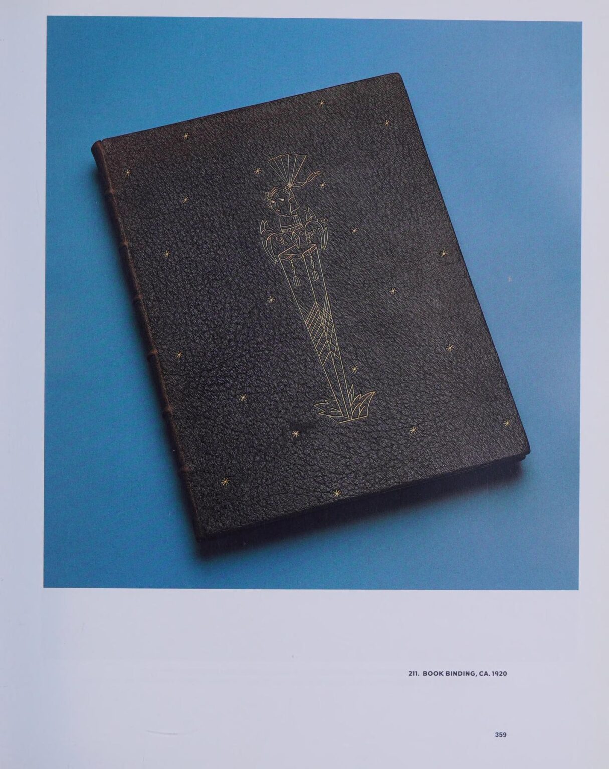 Tooled and gilt black leather book binding featuring a tall central torch-like figure and small scattered gilt stars, on a blue background.